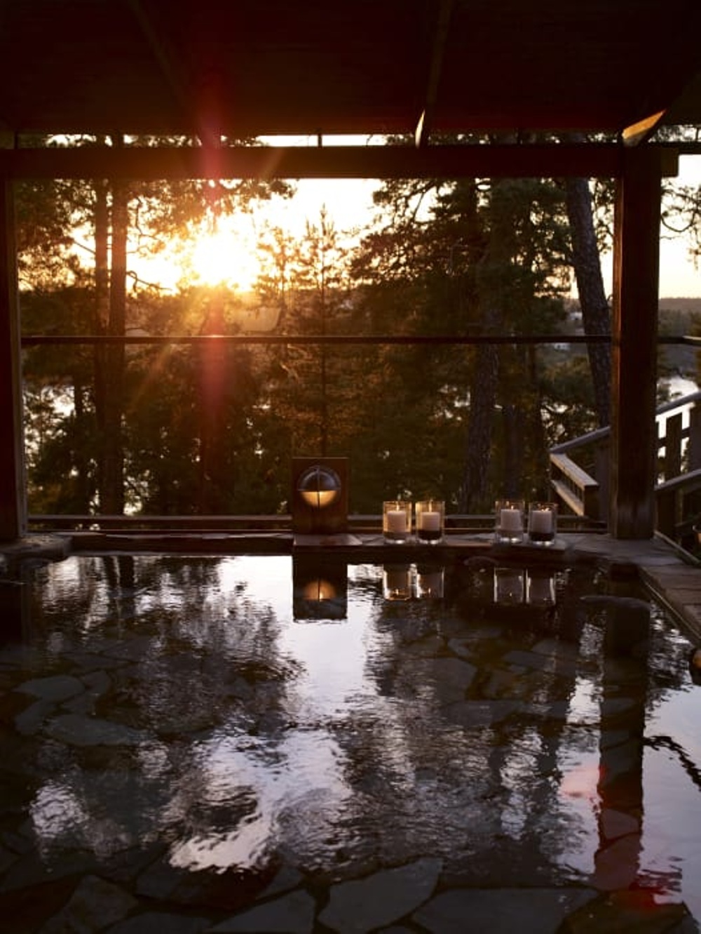 Utomhusbadet på Yasuragi med badet i förgrunden och tallar, vatten och solnedgång i bakgrunden. 