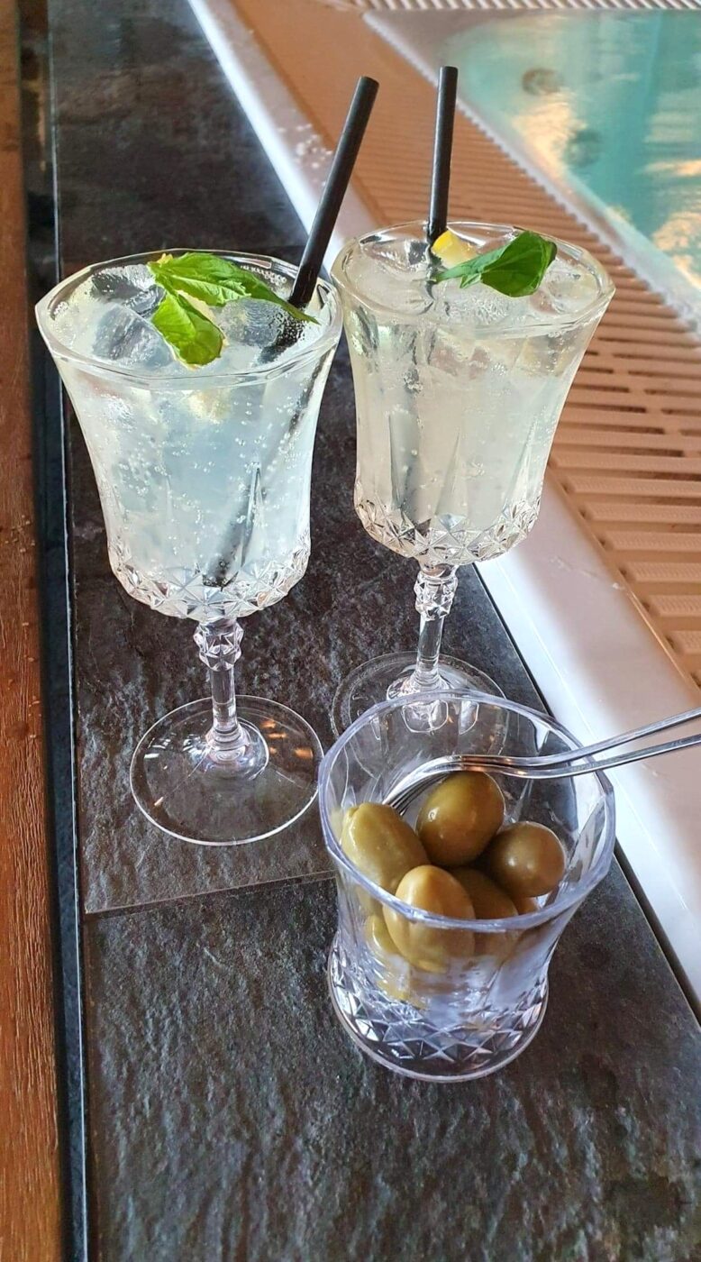 Närbild på två drinkar och ett glas med oliver. 